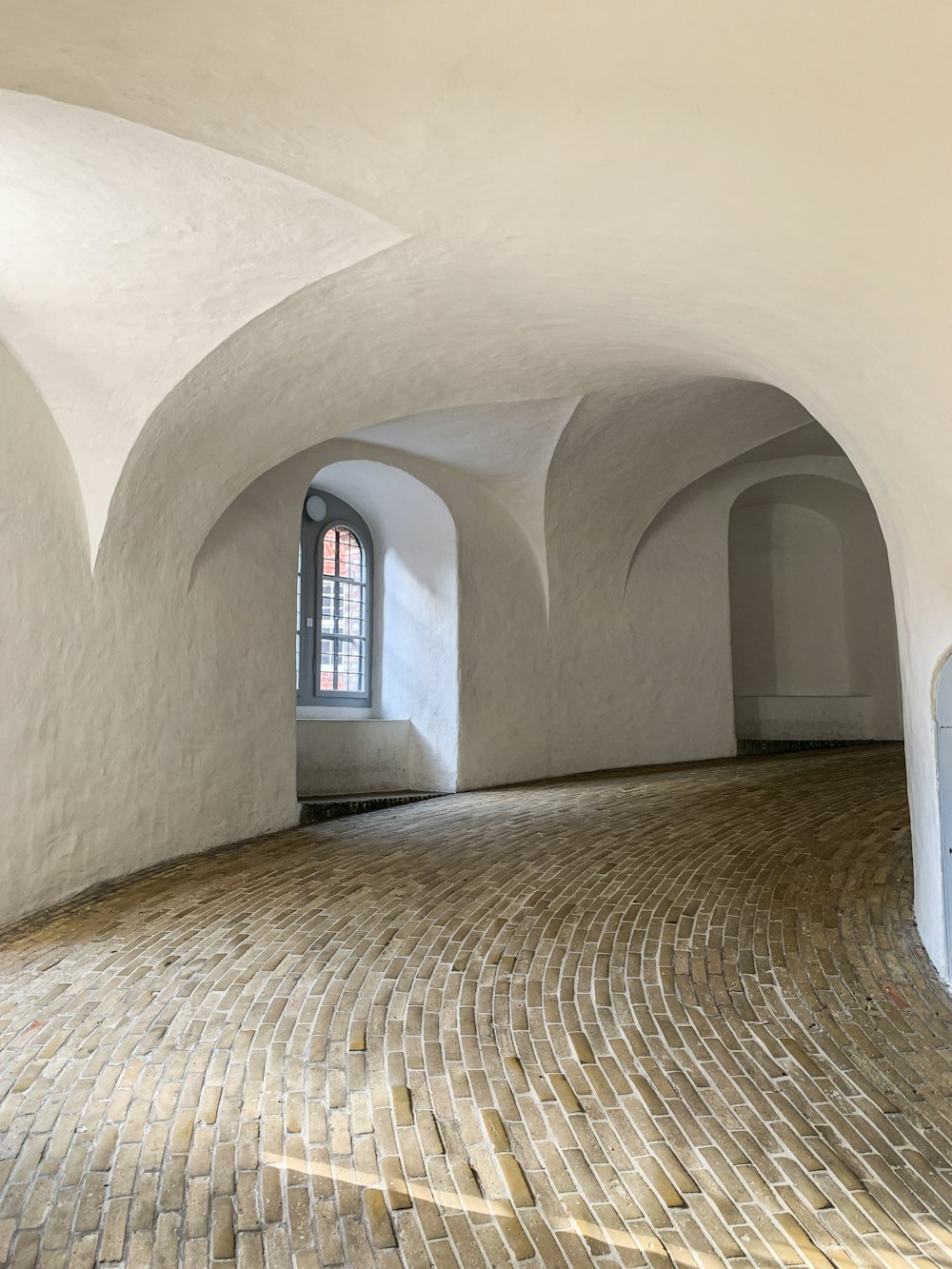 a room with a brick floor and arched windows