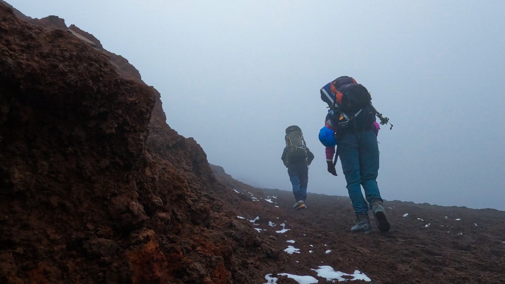 two people hiking up a mountain in the fog