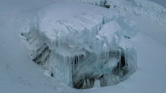 Wide shot of a towering ice mountain with deep blue crevices cutting through its face.