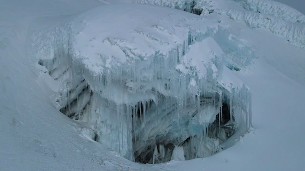 Wide shot of a towering ice mountain with deep blue crevices cutting through its face.