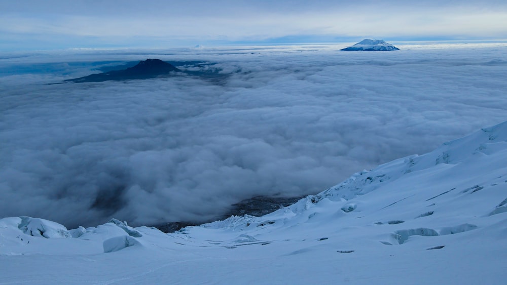 a mountain covered in snow and clouds under a cloudy sky