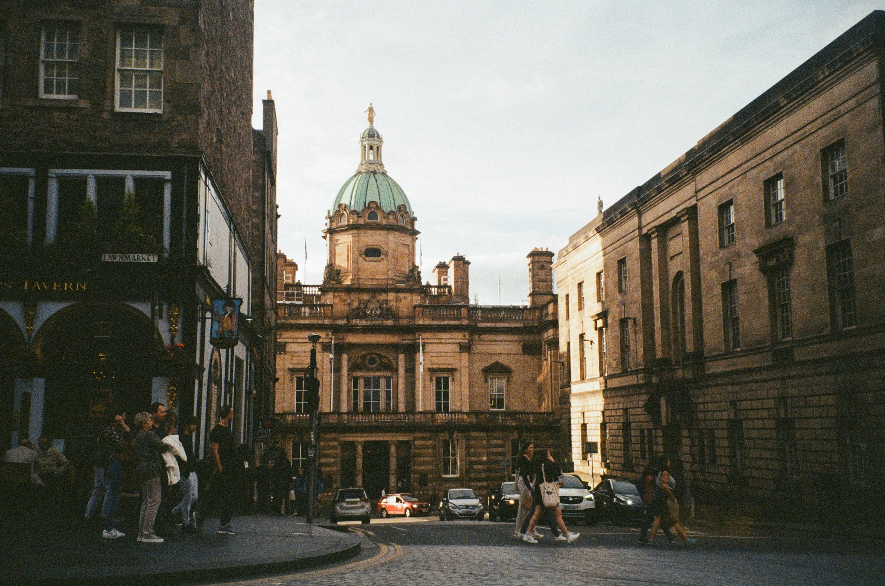 a group of people walking down a street next to tall buildings