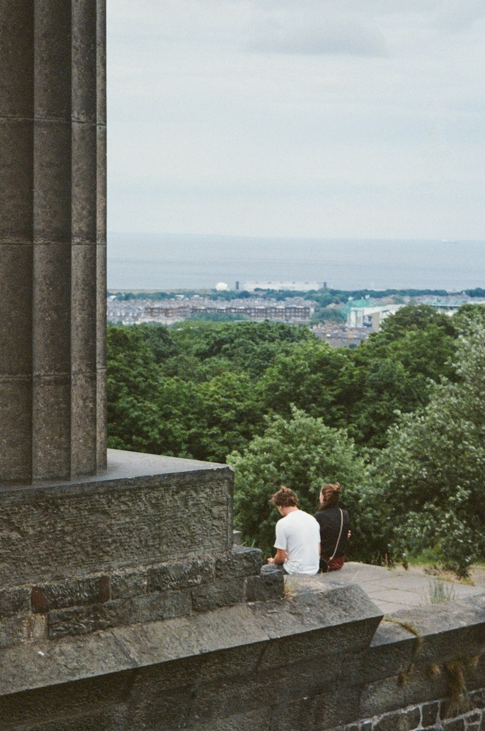 un paio di persone sedute in cima a un muro di pietra