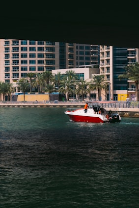 A vibrant photo of a speedboat cutting through the sparkling waters of the New York Harbor with the city skyline in the background under a clear blue sky.