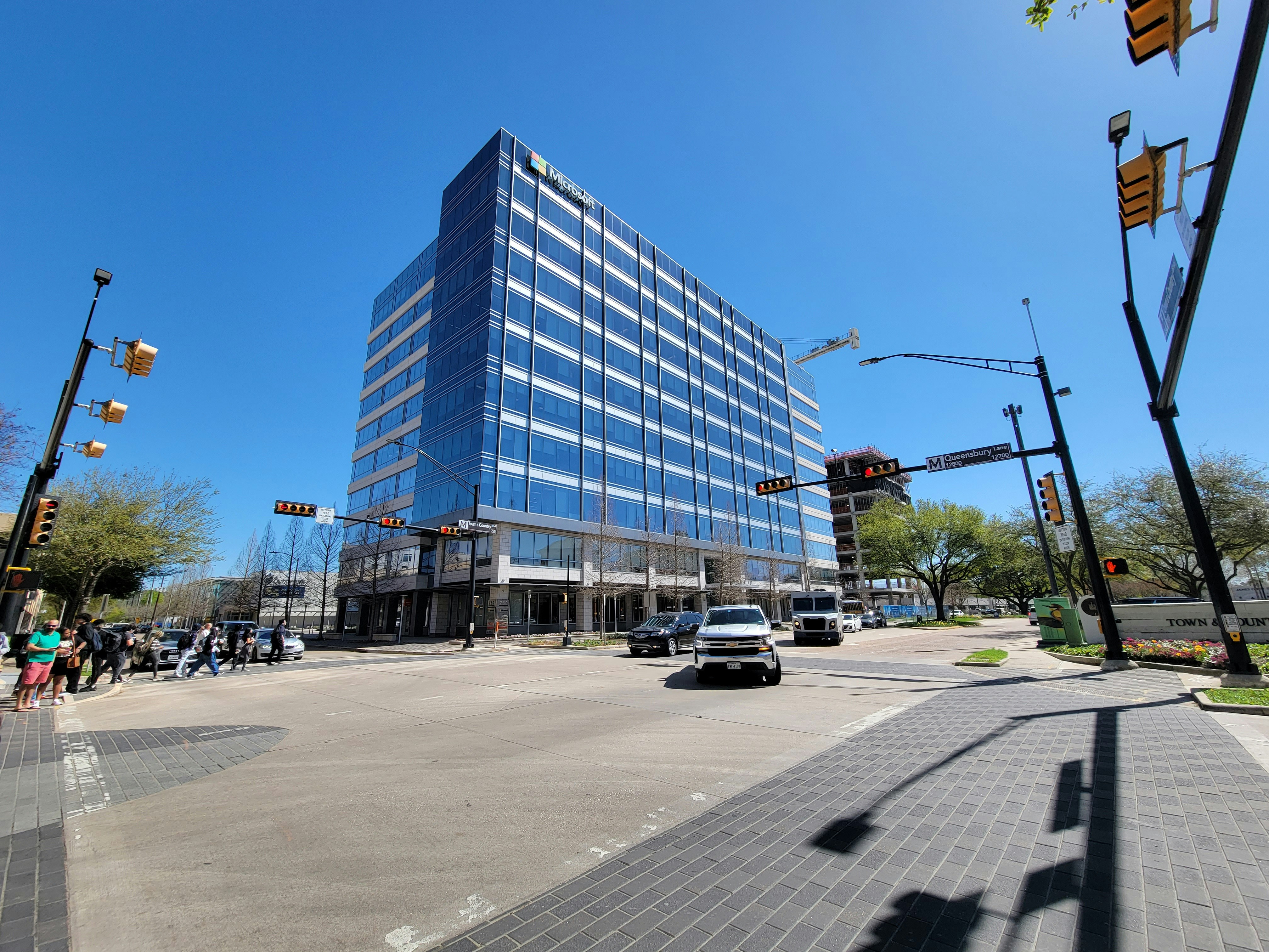 Microsoft logo on glass office building with clear blue sky reflection