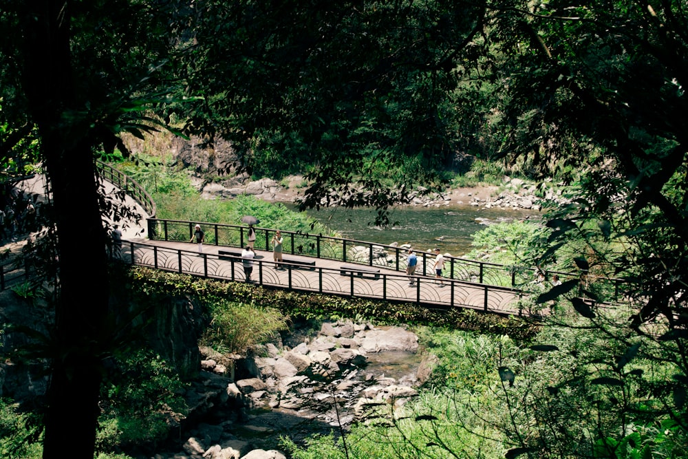 a group of people walking across a bridge over a river