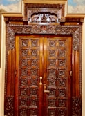 A sturdy wooden front door with intricate carvings and a polished finish.