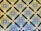 A geometric pattern featuring a repeating diamond motif with intricate tilework. The pattern includes blue circular tiles with white floral designs, contrasted against a background of mint green and brown squares, accented by smaller green and white squares at the intersections.