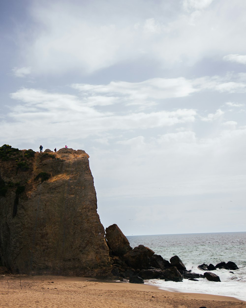 a group of people standing on top of a beach next to the ocean