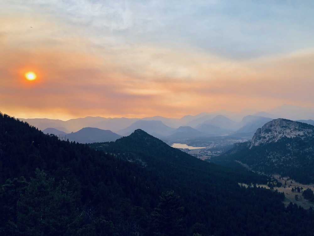 the sun is setting over a mountain range