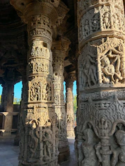 Close-up of intricate carvings being crafted on temple pillars in golden hues.