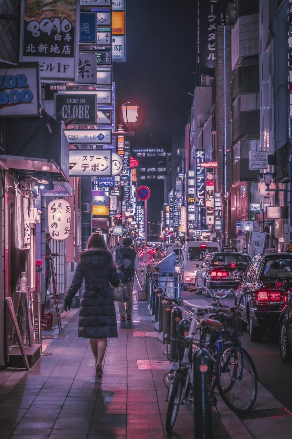 a woman walking down a city street at night