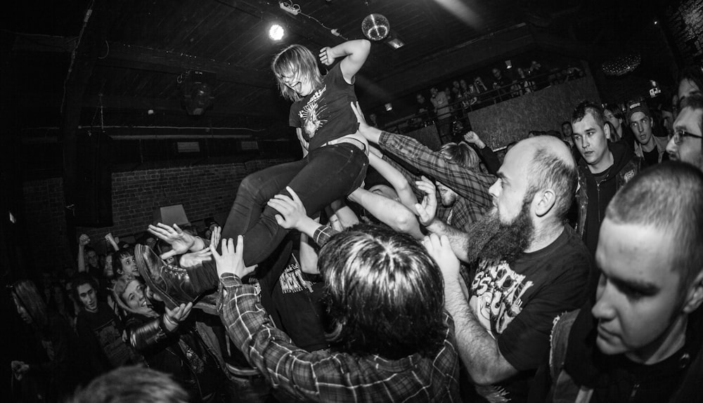 a woman on top of a man in the middle of a crowd