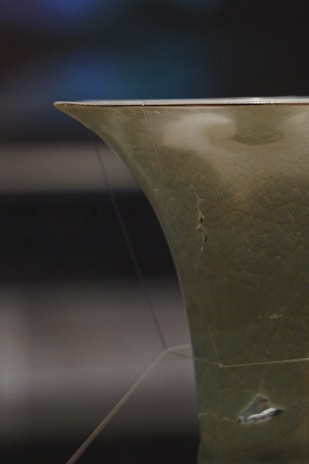 A detailed shot of a ceramic piece glazed with natural materials, resting on a reclaimed wooden pedestal.