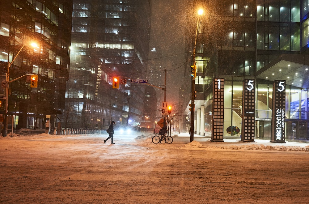 a person crossing a street at night in the snow