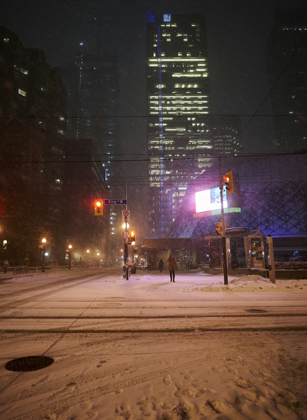 a person walking across a snow covered street at night