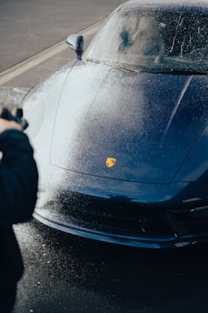 a person taking a picture of a blue sports car for car detailing