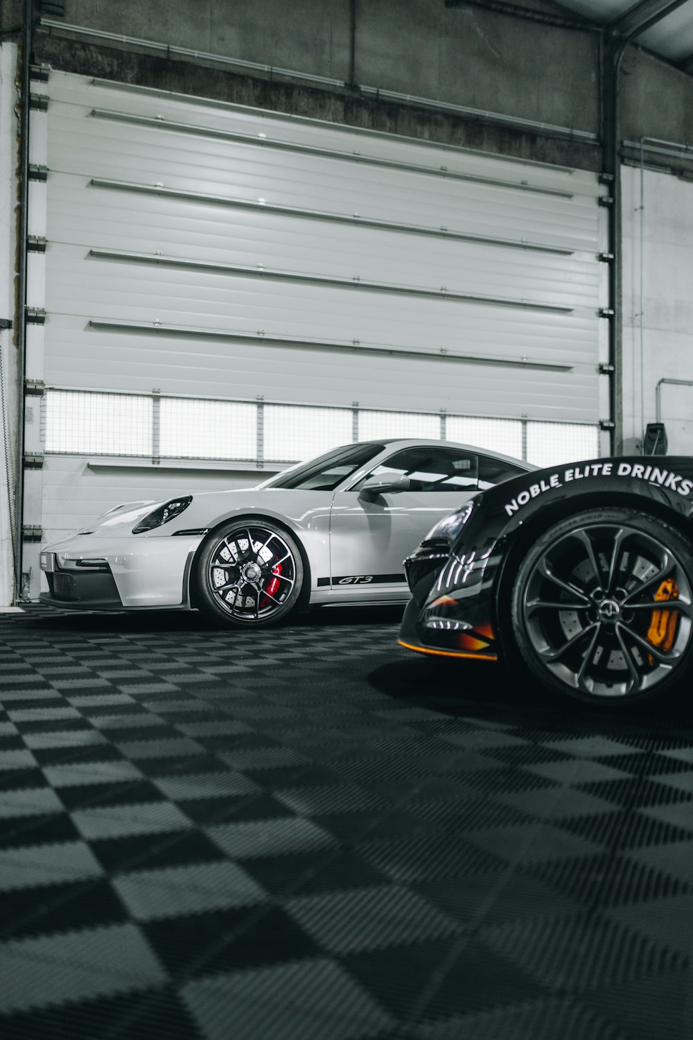 two sports cars parked in a garage next to each other