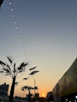 Evening shot of Sudjai Apartment glowing warmly with string lights and palm trees swaying gently.