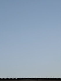 A clean, repaired roof shining under a clear blue sky in a Houston neighborhood.