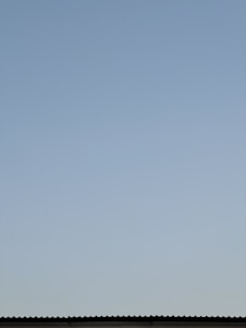 Photo of a skilled roofer repairing a residential roof under a clear blue sky in Garden City.