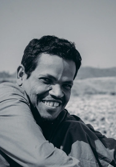 A confident man smiling outdoors, radiating vitality and calm.