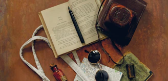 A vintage map spread out on a wooden table beside an old leather-bound journal and a quill pen.