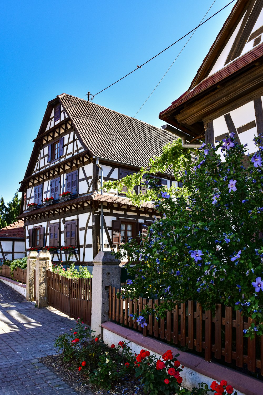 a house with a fence and flowers in front of it