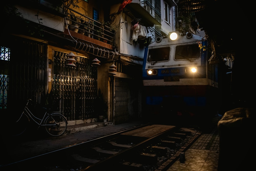 a train traveling down tracks next to a tall building