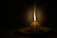 A softly lit candle casting gentle shadows on a cream-colored tablecloth.
