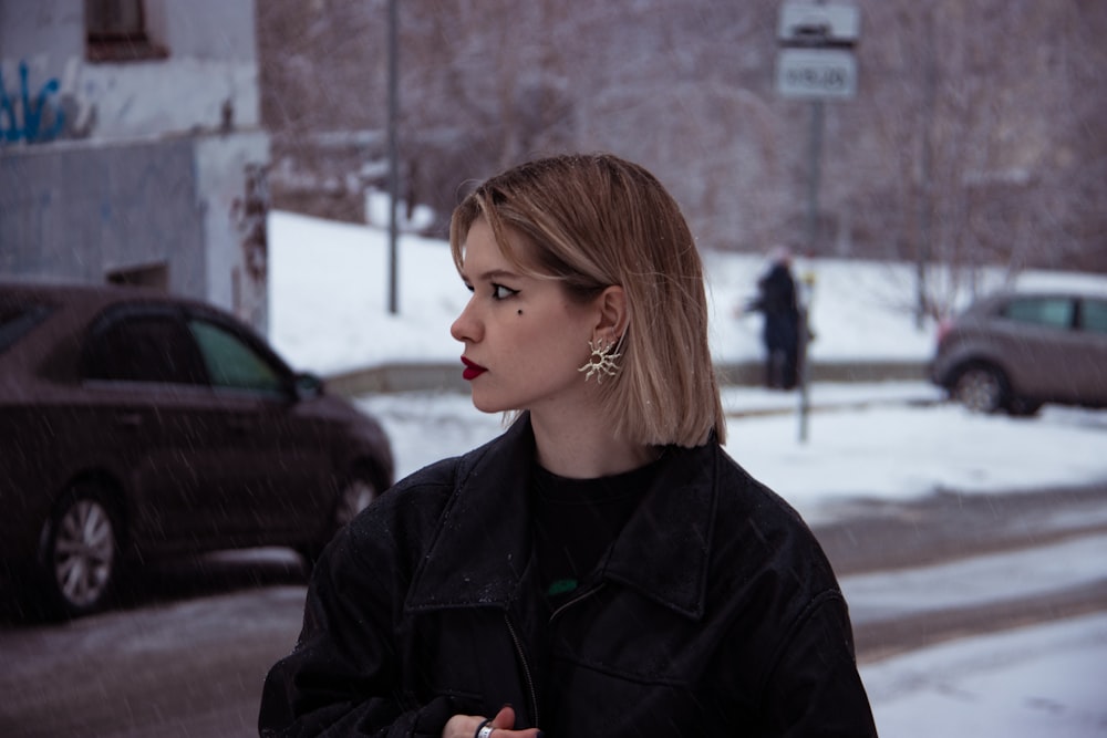 a woman standing on a street corner in the snow