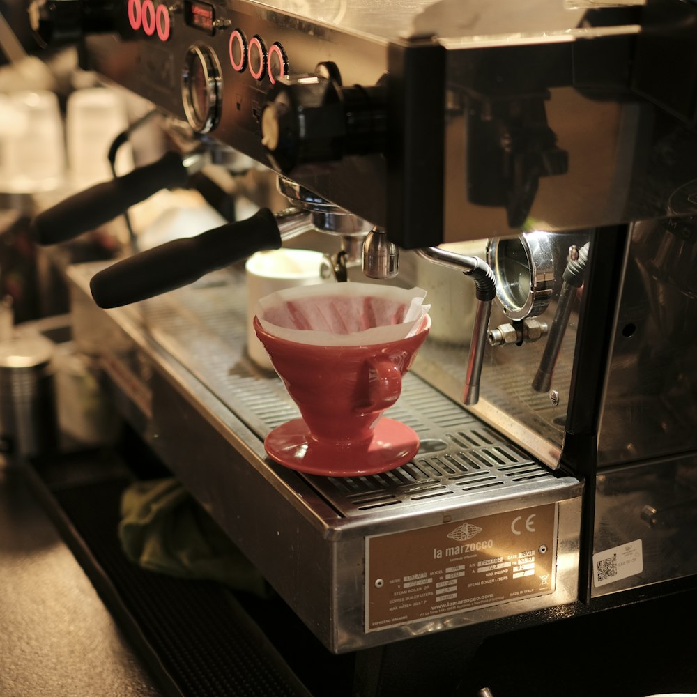 a red coffee cup sitting on top of a machine
