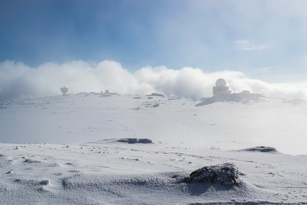 a hill covered in snow and clouds under a blue sky