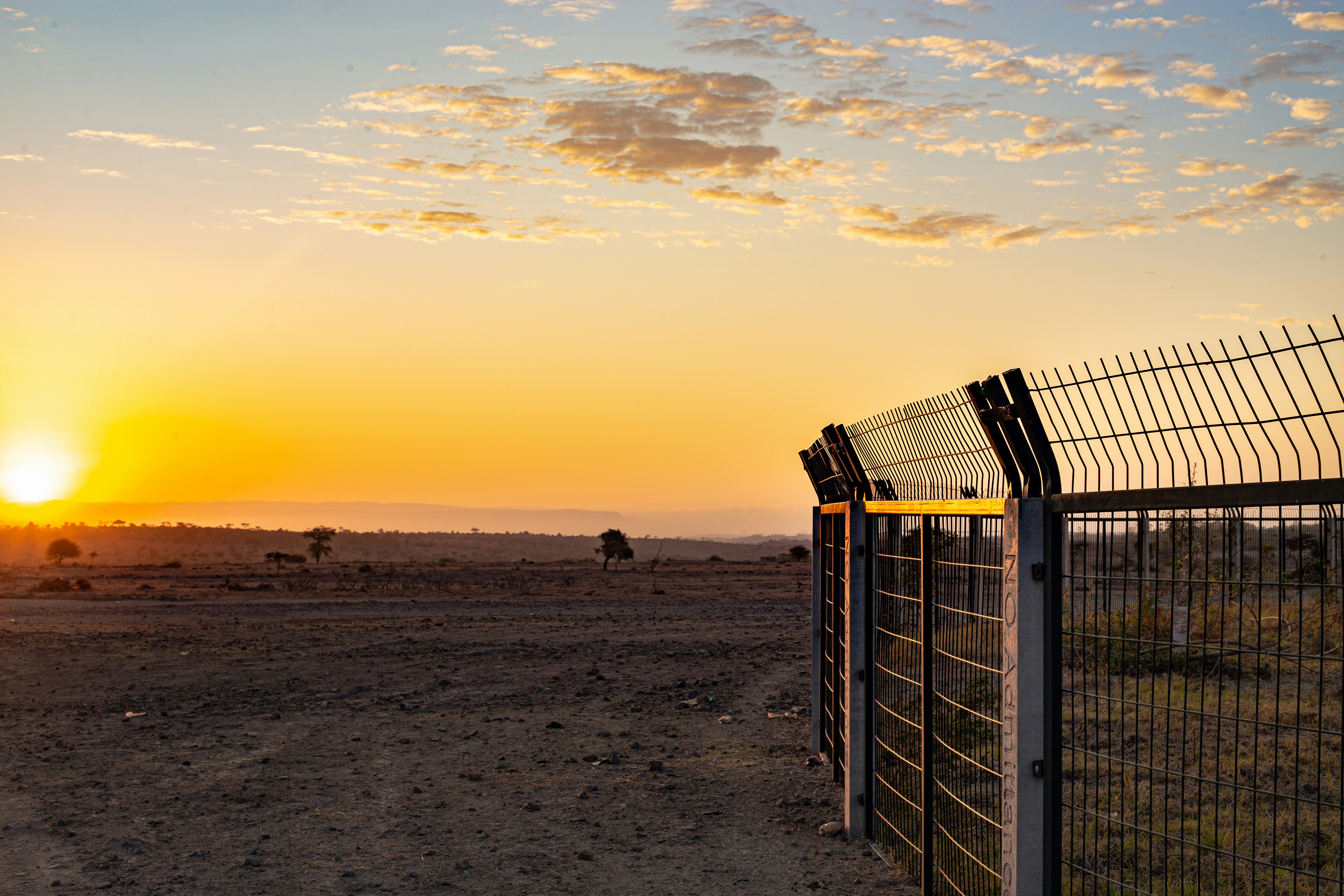 Le soleil se couche derrière une clôture dans le désert