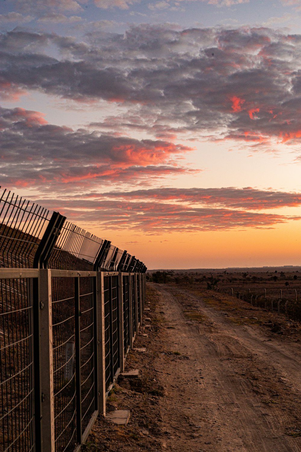 a line of fences along a dirt road