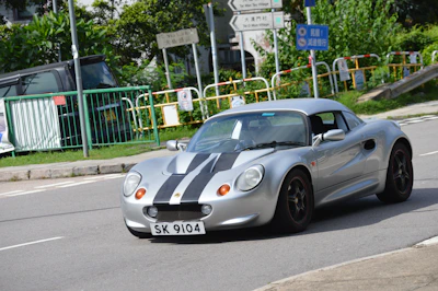 A sleek vintage sports car with retro decals cruising past a rocket-shaped diner.