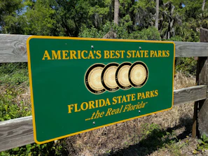 a sign for the florida state parks in front of a wooden fence