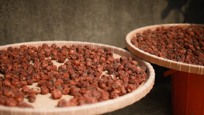 Close-up of sunflower seeds drying in the sun on a traditional bamboo tray.