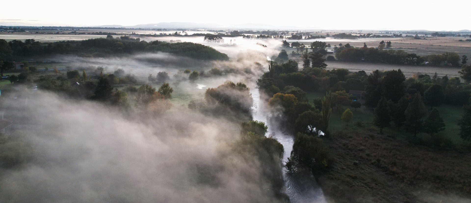 A serene morning view of the Amazon River from Camungo Lodge, with mist rising over lush green foliage.