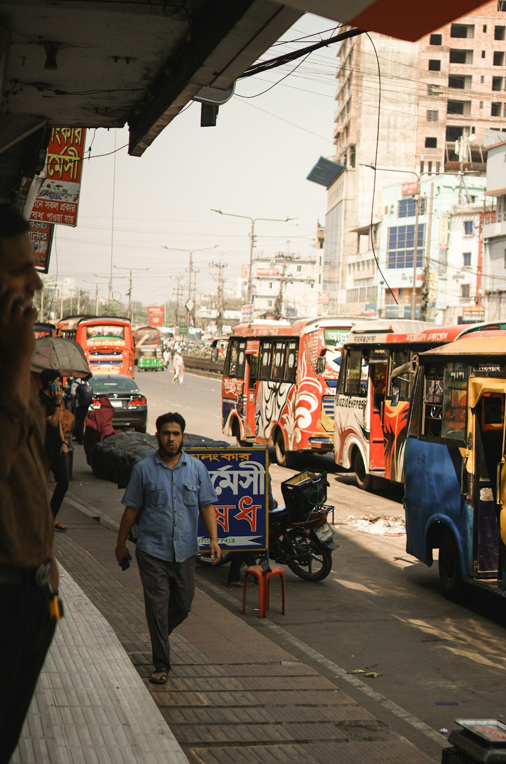 a man walking down a street next to parked buses