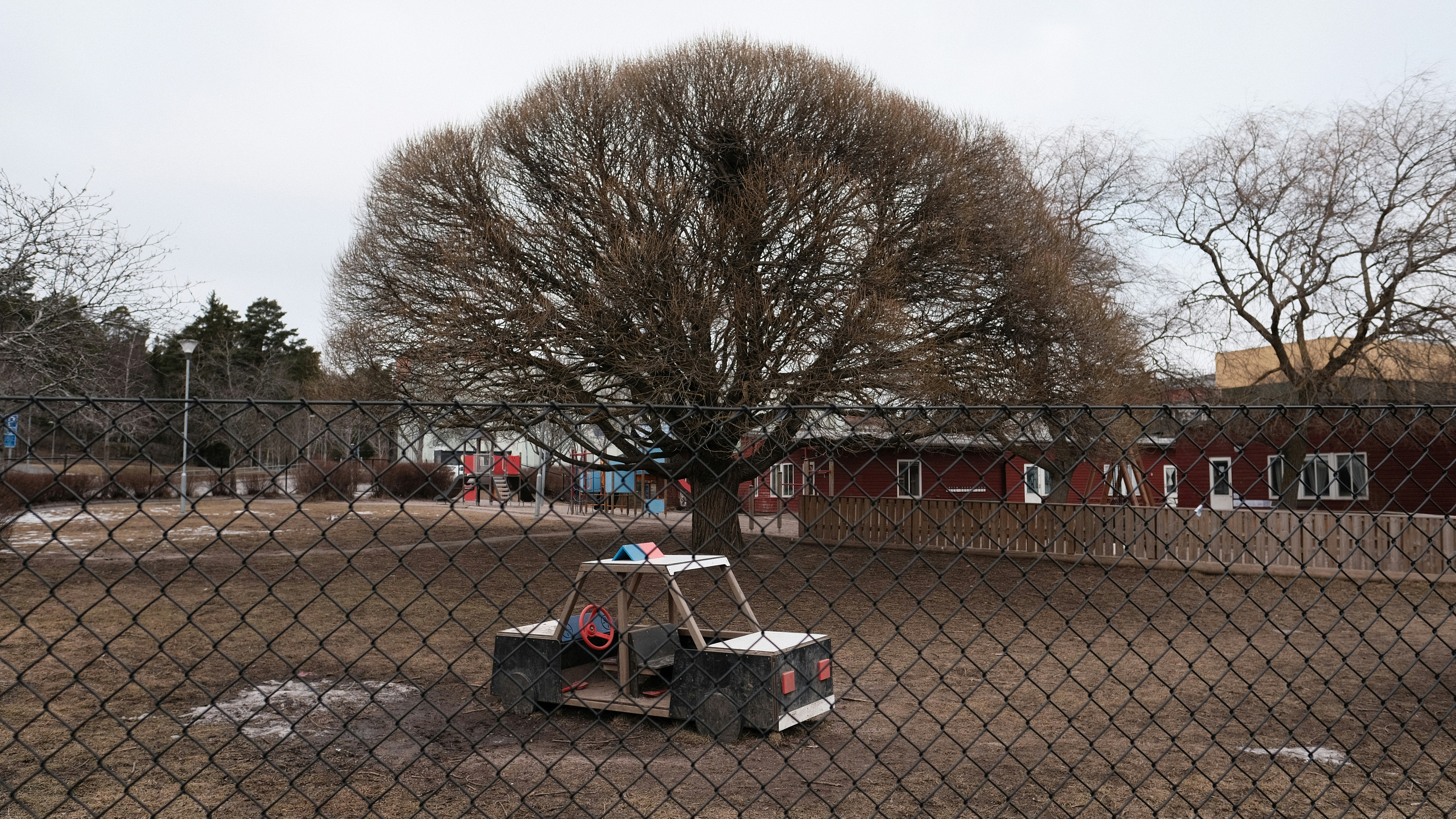 un petit chariot assis dans un terrain de terre derrière une clôture à mailles de chaîne