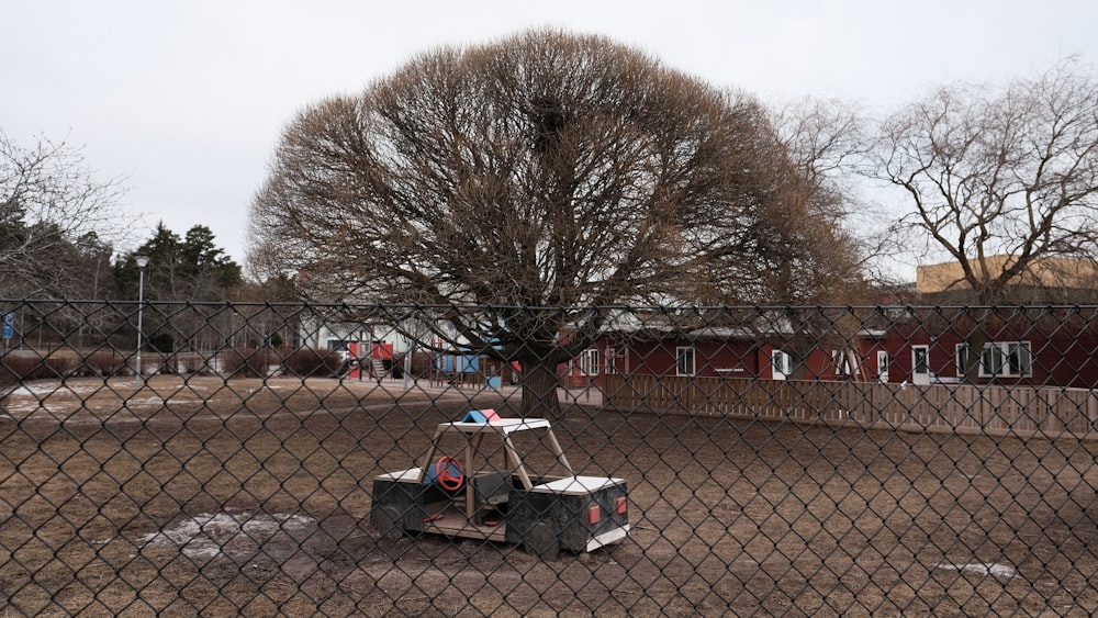 un piccolo carrello seduto in un terreno sporco dietro una recinzione a catena