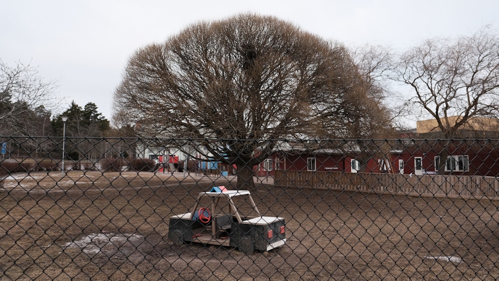 Un pequeño carrito sentado en un lote de tierra detrás de una cerca de alambre