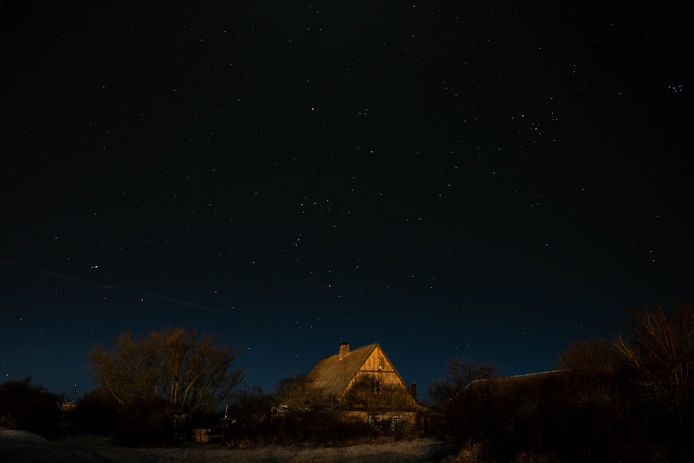 a house with a thatched roof is lit up at night