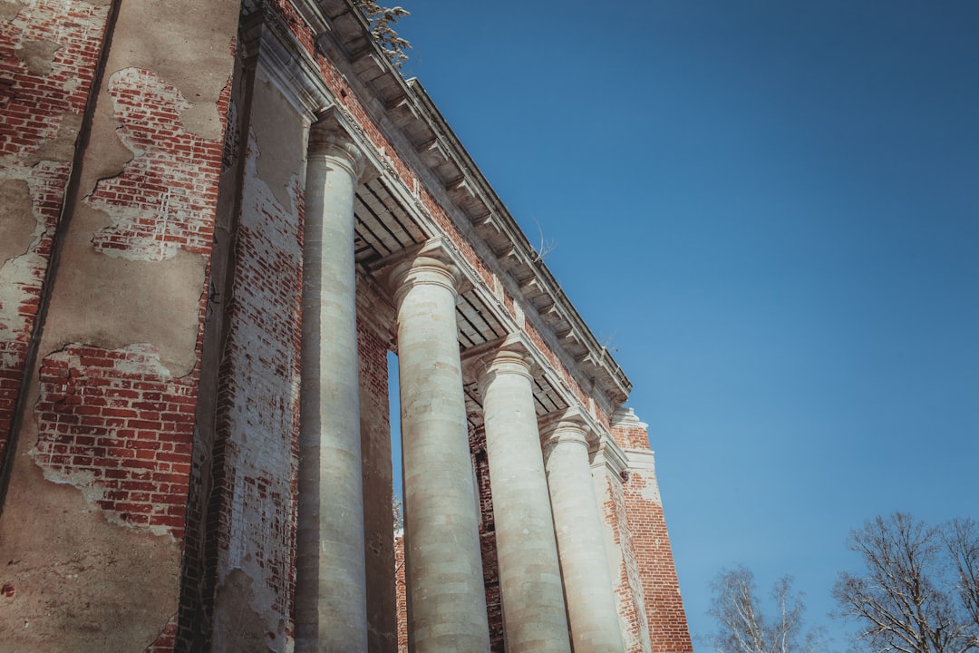 a tall brick building with two large pillars, Abandoned House