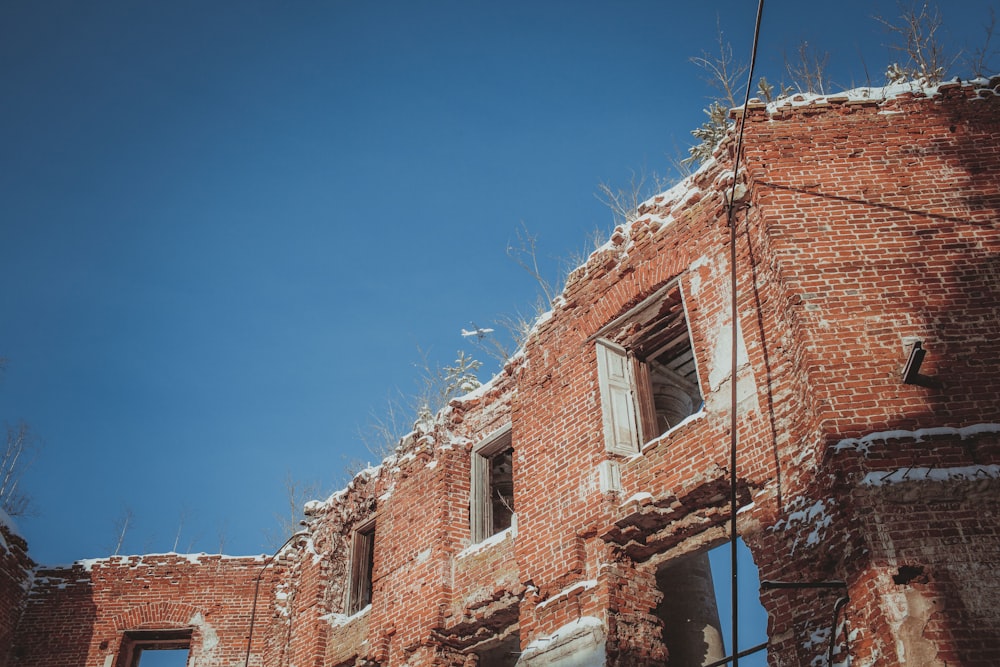 Un vieux bâtiment en briques avec des fenêtres brisées par une journée ensoleillée