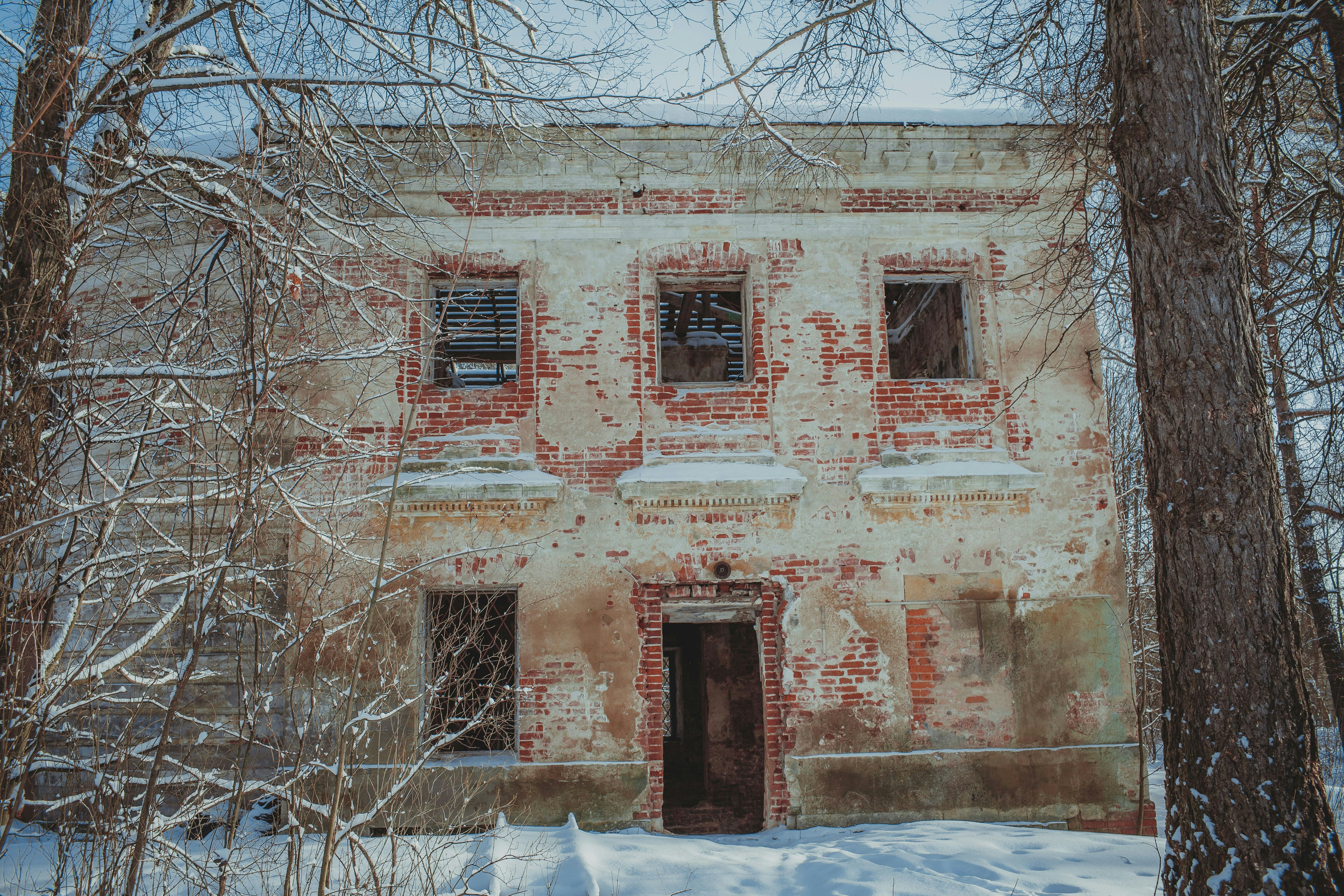 an old brick building surrounded by trees and snow