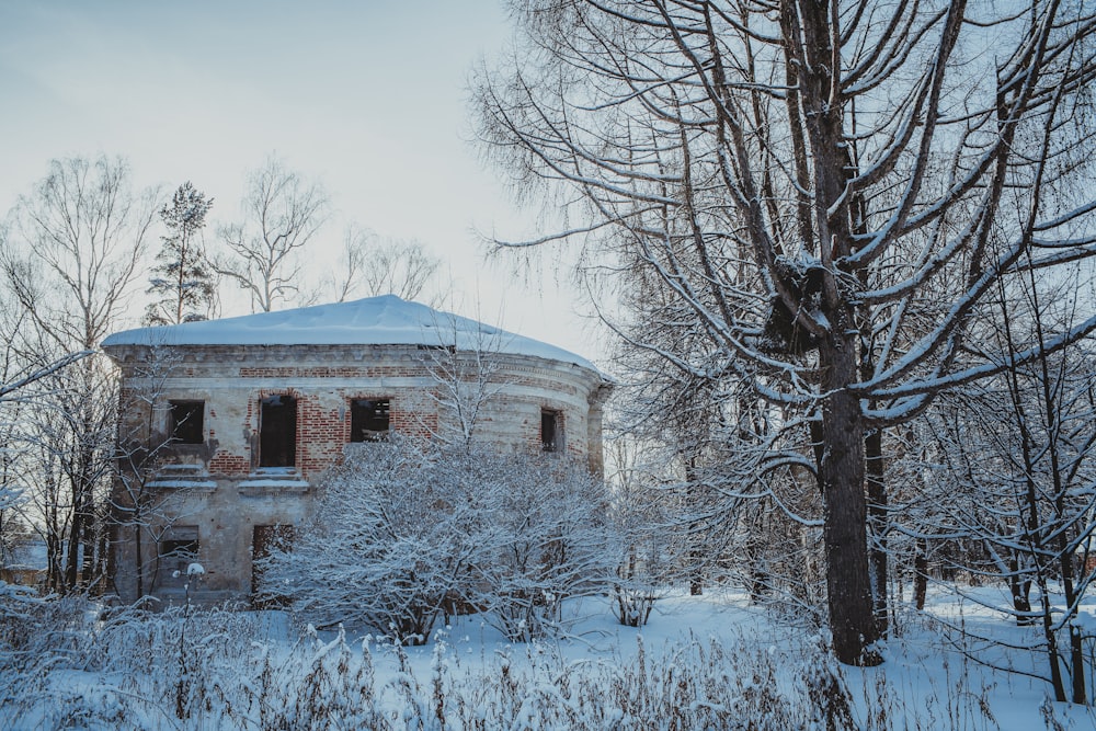 an old building surrounded by snow covered trees