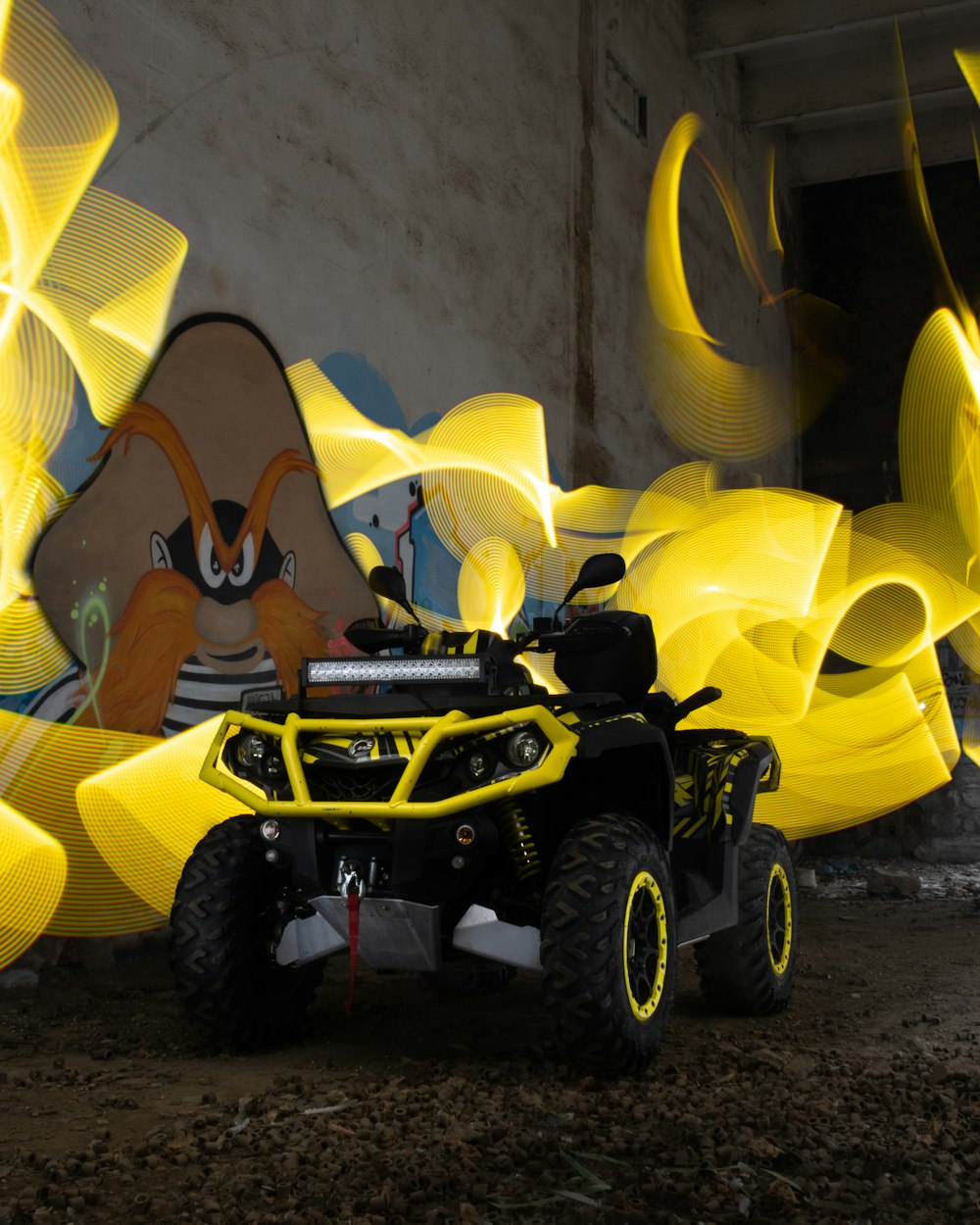 a yellow four - wheeler parked in front of a graffiti covered wall