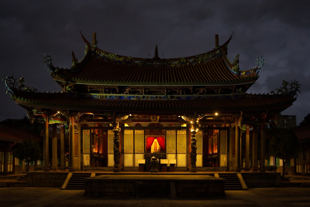 a building lit up at night with a person sitting in the doorway